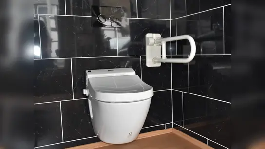 Diese Toilette wurde erhöht aufgehängt und mit einem stabilen Haltegriff ausgestattet. Ein beheizbarer Wassertank bietet eine Sprühfunktion zum Waschen des Intimbereichs, die per Fernbedienung gesteuert wird.  (Foto: Barbara Siebrecht)